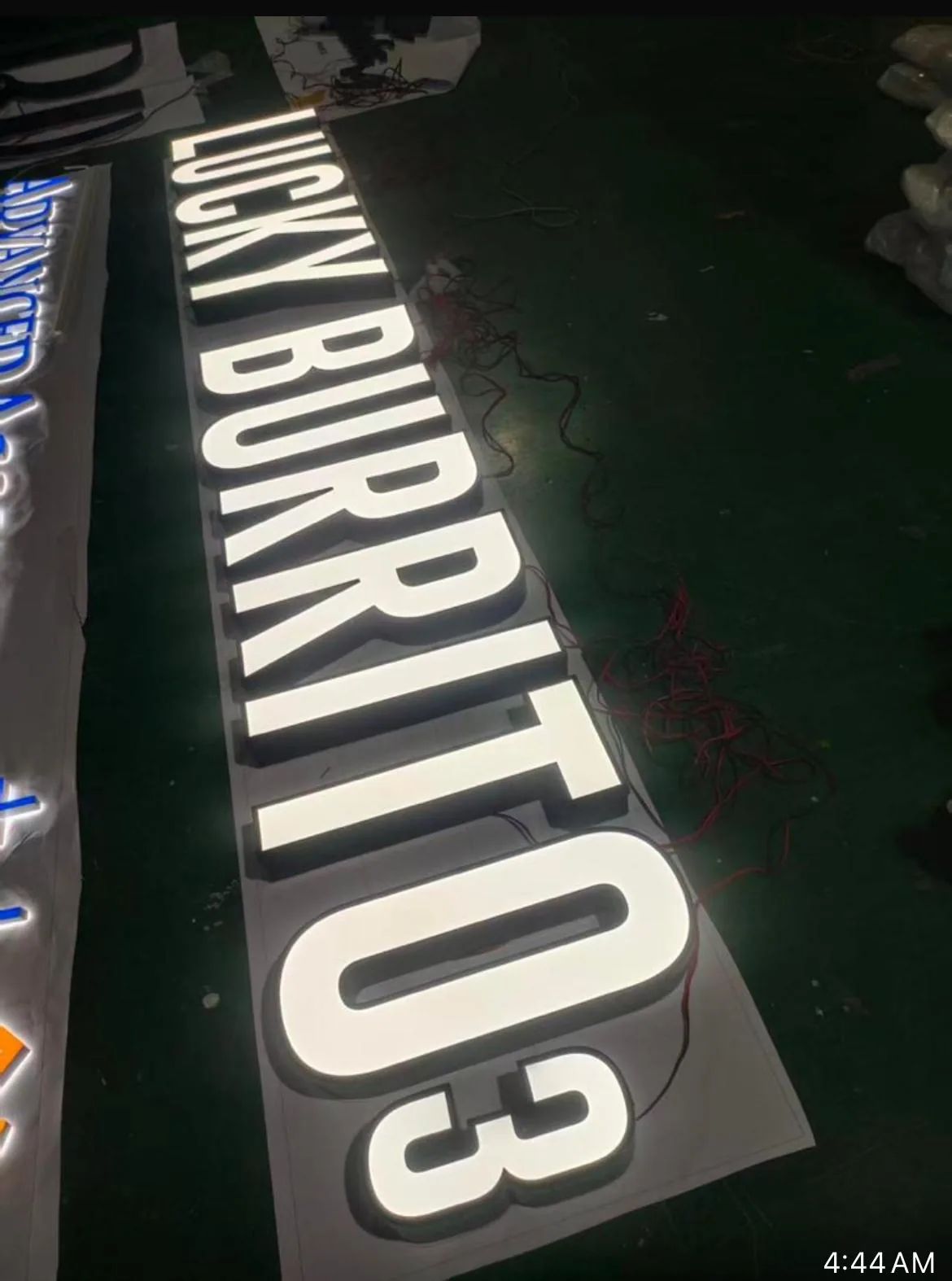 LUCKY BURRITO channel letters lit up on the shop floor, seen from the end of the row.