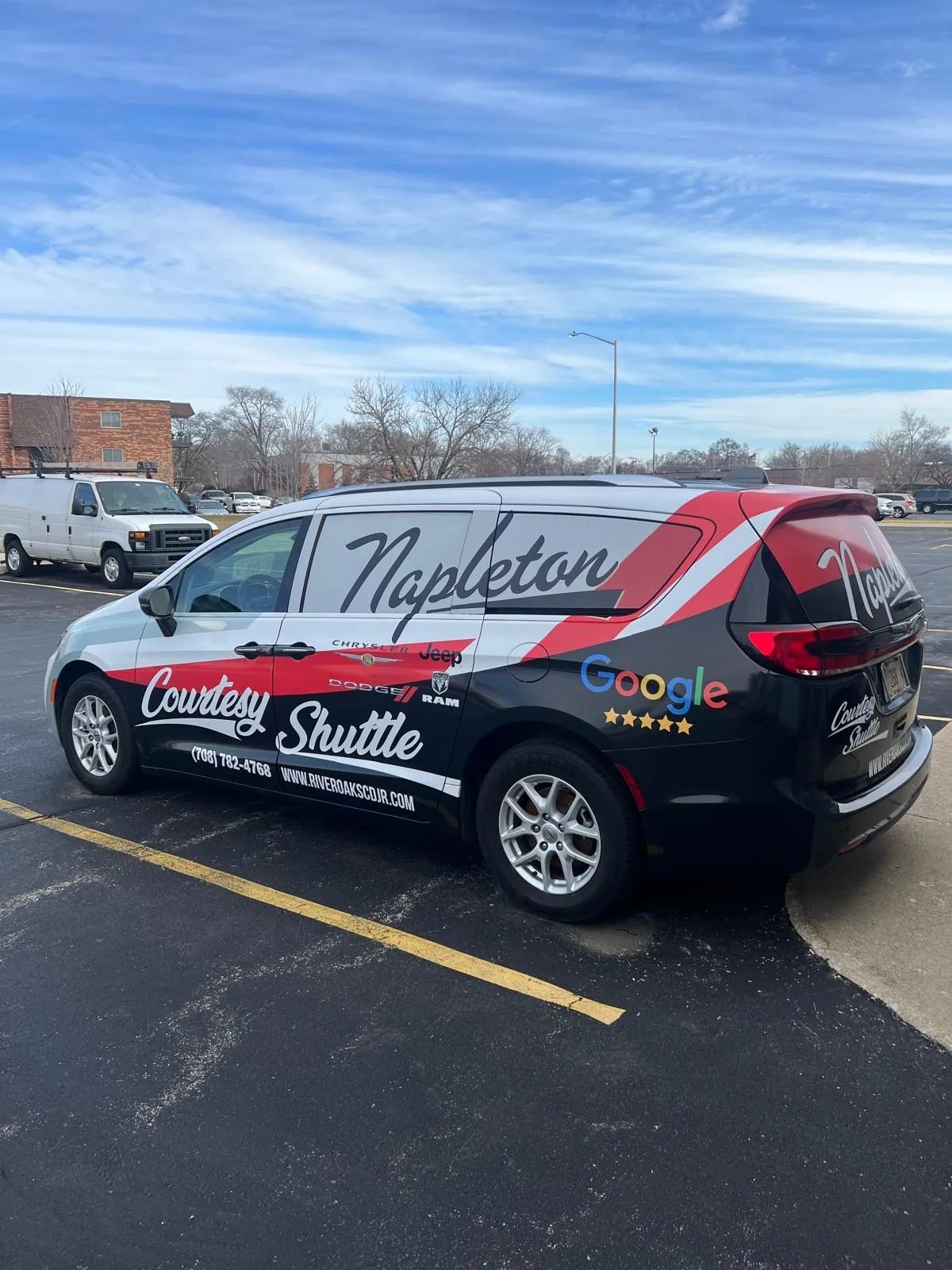 White Chevrolet SUV with Napleton Courtesy Shuttle lettering and a red and black stripe wrap, in a snowy lot.