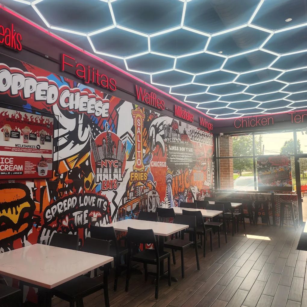 Restaurant dining room with an illustrated mural along the wall, red neon menu lettering and a hexagonal LED ceiling.