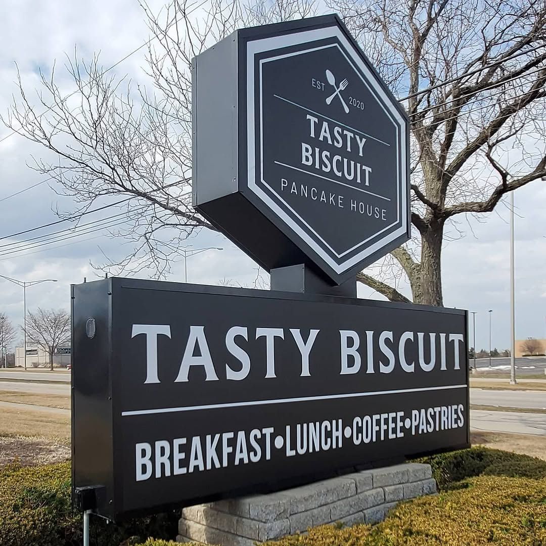 Tasty Biscuit pancake house monument sign on a stone base with a hexagonal cabinet sign on a pole above it.