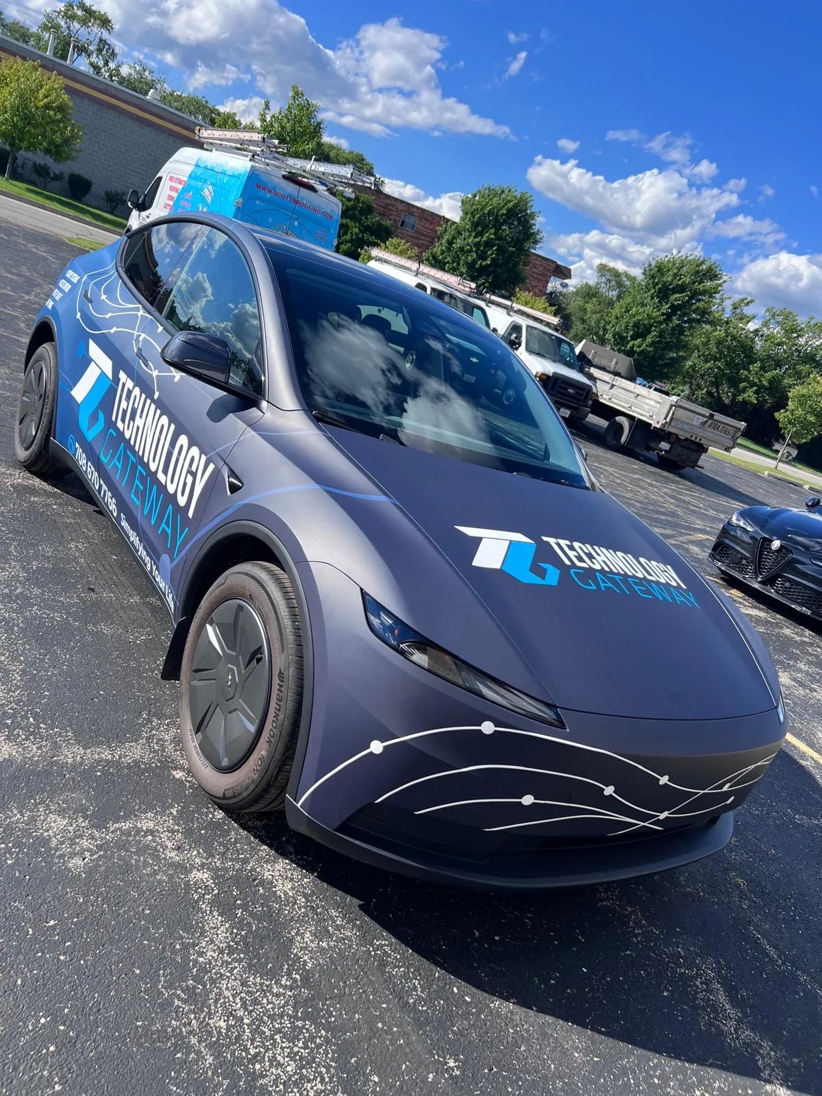 Blue Tesla Model Y in a Technology Gateway wrap with a circuit-line graphic flowing over the hood and doors.