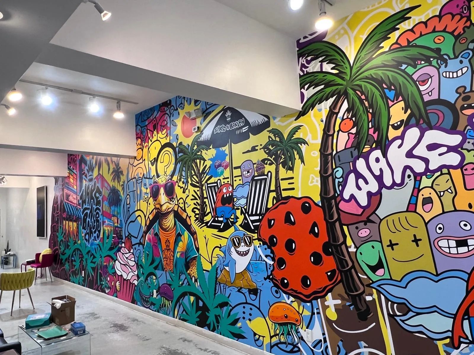 Inside Wake n Bakery: a wall-to-wall printed mural of cartoon characters, palm trees and the WAKE lettering.