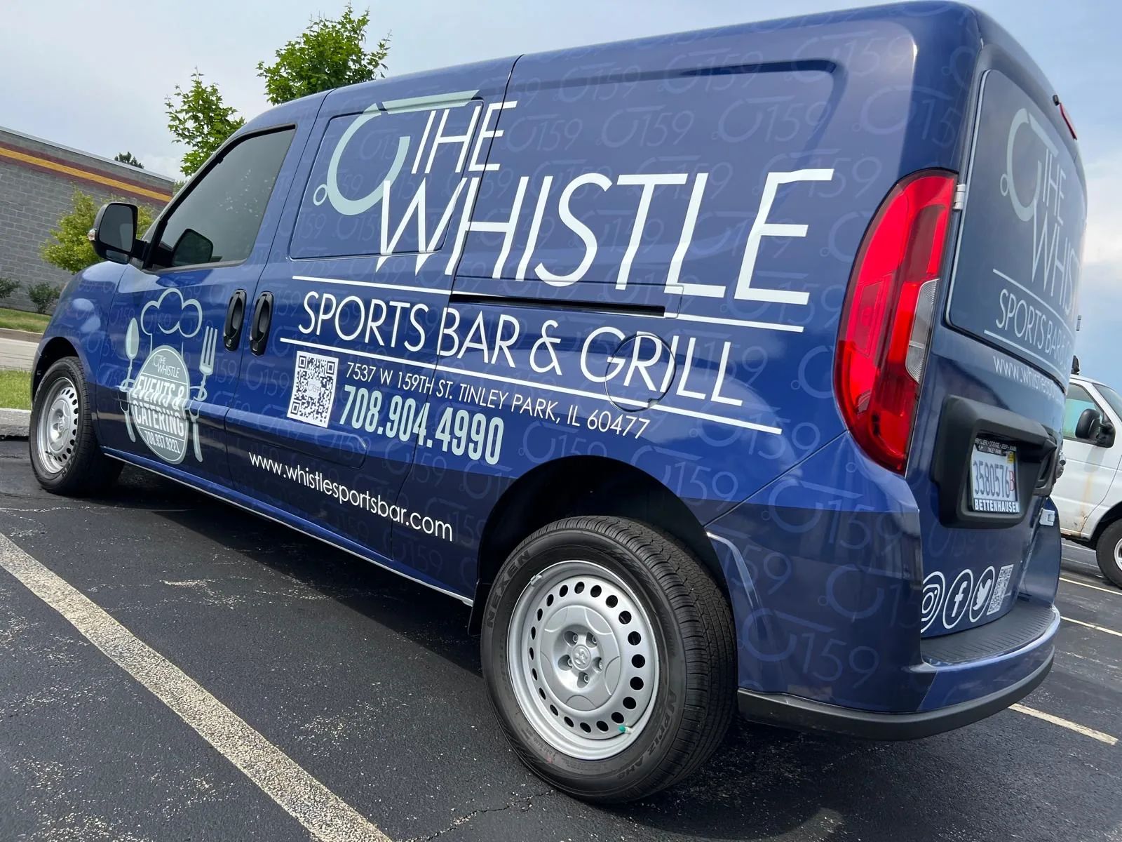 Dark blue Ram ProMaster City van wrapped for The Whistle Sports Bar & Grill, with the logo, phone number and website along the side.