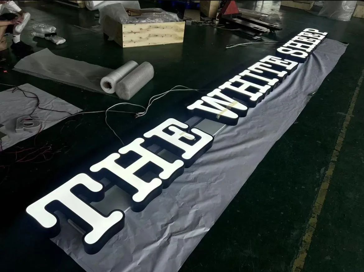 Large white THE WHITE SHEEP letters laid out on a black banner on the shop floor.