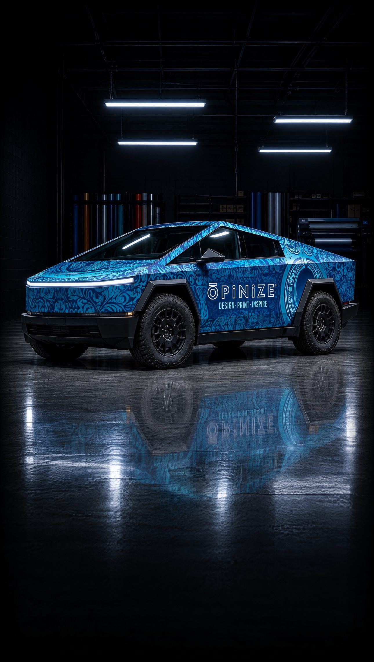 The Opinize Design pickup truck in a full blue paisley wrap, parked side-on in the shop's garage bay under the lights